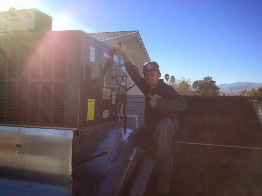 HVAC technician performing Boiler Repair on a rooftop unit in Adams
